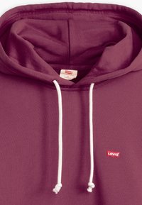 Burgundská mikina s kapucí vyrobená z jemného materiálu, vybavená bílou šňůrkou, přední kapsou a malou červenou cedulkou Levi's na hrudi.
