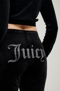 Melni siltie bikses ar rhinestone "Juicy" logo aizmugurē. Dizains ietver mīkstu tekstūru un elastīgu jostu.