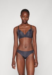 Reggiseno seamless nero e bikini coordinato, caratterizzati da una superficie liscia, design a V e spalline sottili. Stile minimalista senza decorazioni.