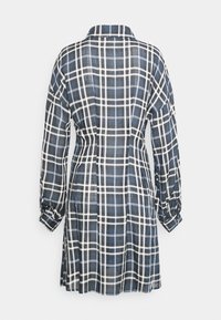 Vestido xadrez de mangas longas, com as cores azul, preto e branco. O tecido tem uma textura suave e um corte descontraído, com colarinho e costas pregueadas.