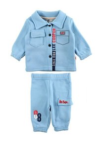 Ensemble deux pièces bleu clair en tissu doux. La chemise comporte un col, des boutons et des patchs décoratifs ; le pantalon dispose de poches latérales et d'accents.