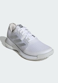 Scarpa da ginnastica bianca con tomaia in mesh testurizzato, tre strisce grigie sul lato e un colletto imbottito. Presenta una suola in gomma liscia.
