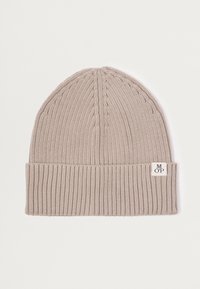 Knitted beanie in light beige with ribbed bottom. Features cable knit texture on top and a small brand tag on the side.