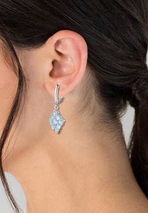 Sølv hoopsmykke med en diamantformet vedhæng pyntet med lyseblå ædelsten, der viser en poleret overflade og indviklede detaljer.