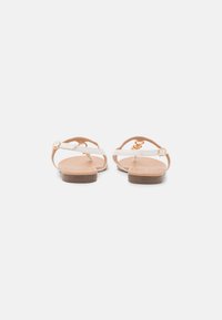 Sandales blanches en cuir avec un design à tongs, une bride arrière et des accessoires en ton doré. Semelle en caoutchouc plate avec une finition marron clair.