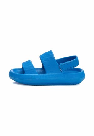 Sandalias azules con un material de goma texturizado, dos correas ajustables, una suela plana y un lazo en el talón trasero para ponerlas y quitarlas fácilmente.