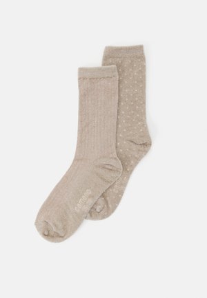 Two beige cozy socks, one with subtle vertical stripes and the other with small polka dots, laid flat on a white background.