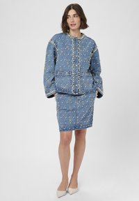 Denim jacket and skirt set with pearl and diamond-patterned embellishments, featuring a quilted design. Light blue color, long sleeves, front buttons.
