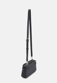 Svart texturerad axelväska med guldfärgad hårdvara, dubbel dragkedjeslutning och justerbar rem. Har ett präglat mönster på kroppen.