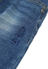 Jean en denim bleu à effet délavé avec finition texturée. Présente une légère décoloration, un logo brodé sur la jambe inférieure et des détails en boutons métalliques.