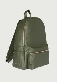 Zaino in pelle verde con forma arrotondata, dotato di un compartimento principale con zip e una tasca frontale con zip. Superficie texture con dettagli in hardware dorato.