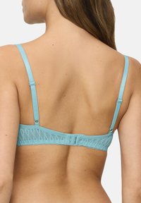 Světle modrá krajková podprsenka s vlnkovým okrajem, nastavitelnými ramínky a zapínáním na háček a oko na zadní straně. Měkká, strukturovaná látka.