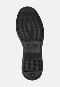Talpa de pantof din cauciuc negru, cu modele texturate pentru aderență, având logo-ul "Camper" embosat în centru. Durabilă și concepută pentru tracțiune.