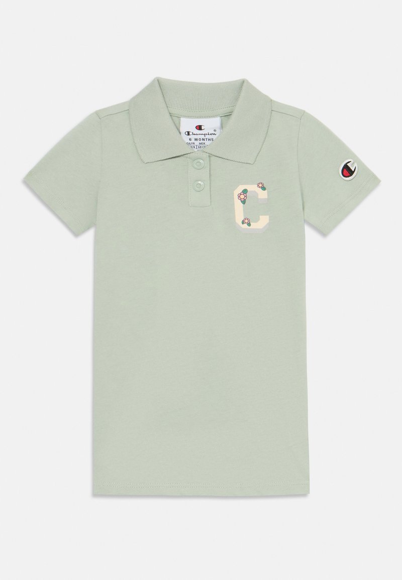Šviesiai žalia polo marškiniai, pagaminti iš medvilnės. Su apykakle, dviem mygtukais ir gėlių siuvinėtu "C" logotipu ant krūtinės. Trumpomis rankovėmis.