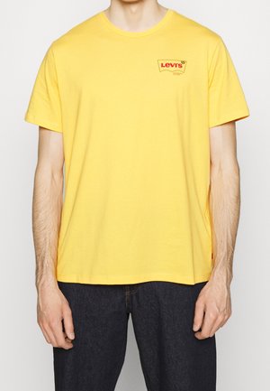 T-shirt en coton jaune avec un petit logo rouge Levi's sur la poitrine gauche. Manches courtes, col rond et coupe décontractée.