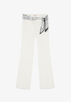 White high-waist pants with a flared leg and a tied black and white paisley-patterned scarf belt at the waist.