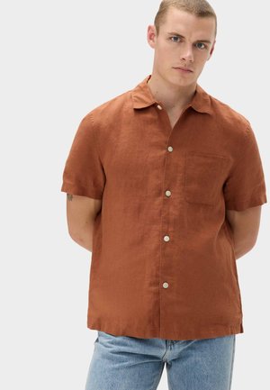 Camisa de manga corta con botones en lino color óxido. Cuenta con un bolsillo en el pecho izquierdo y un cuello estándar, con botones delanteros y un ajuste relajado.