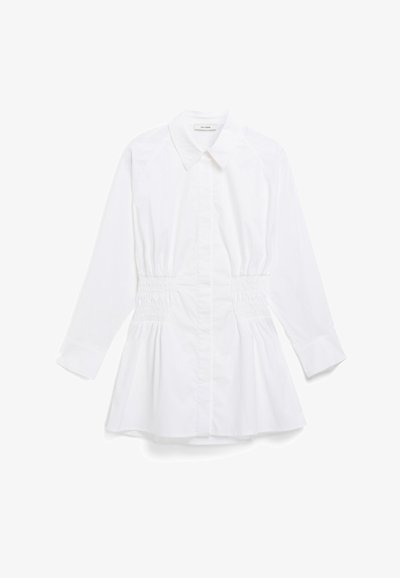 Cămașă albă cu mâneci lungi, gât cu guler, talie elastică și tiv peplum; confecționată dintr-un material neted și ușor.