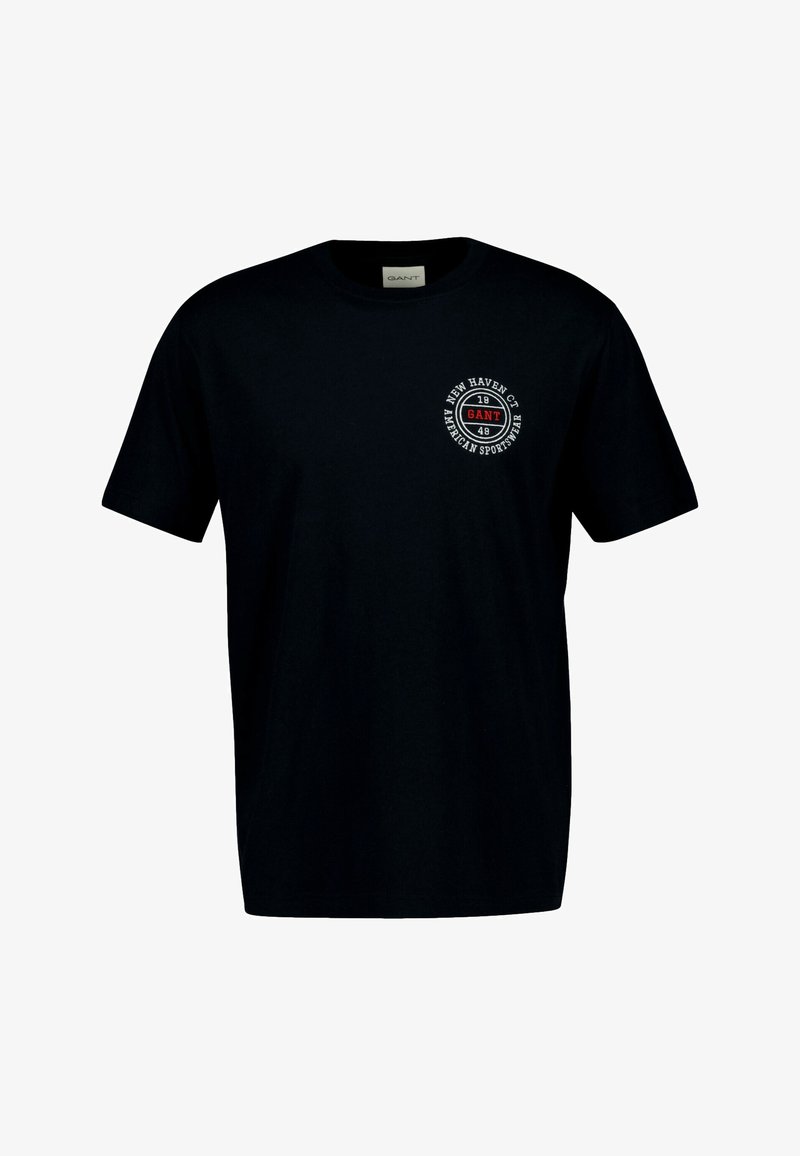 Fekete pamut póló, kerek nyakkivágással és rövid ujjakkal. A mellrészen egy kör alakú, fehér és piros szöveggel ellátott logó található.