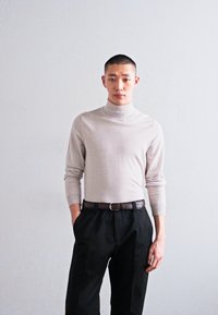 Light gray turtleneck sweater with long sleeves, made of a soft fabric, paired with black tailored trousers and a dark belt.