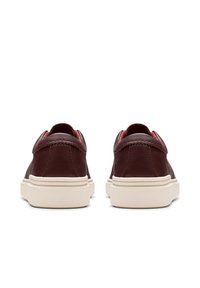 Sneaker in pelle marrone con una superficie liscia, suola in gomma bianca e colletto imbottito alla caviglia. Il tacco presenta un delicato dettaglio di cucitura.