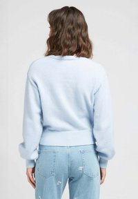 Pull en tricot doux bleu clair avec un col rond et un ourlet côtelé. Assorti à un jean bleu clair avec de petits broderies florales blanches.