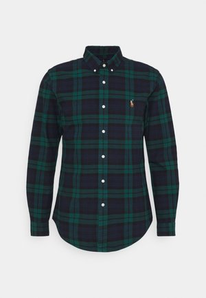 Koszula z długim rękawem zapinana na guziki w ciemnozieloną i granatową kratę z małym haftowanym pomarańczowo-białym logo na lewej piersi.