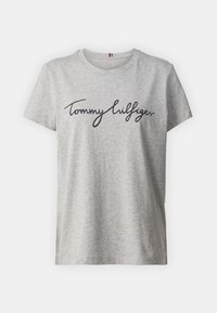 Camiseta de algodón gris con mangas cortas, que presenta un logo en cursiva negro "Tommy Hilfiger" en el frente y un cuello redondo.