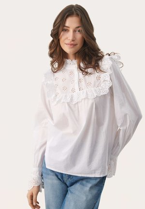 Weiße Baumwollbluse mit einem gerafften Spitzenüberzug mit floralen Ausschnitten, langen puffigen Ärmeln und detaillierten Spitzenmanschetten.