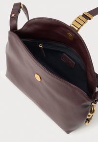 Tumši brūns ādas pleca soma ar zelta furnitūru, atvērta vāka, regulējams siksna un melna iekšējā kabata ar rāvējslēdzēju.