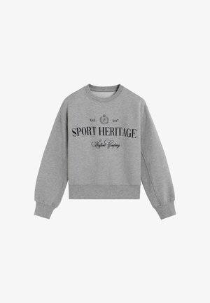 Sudadera gris con un clásico cuello redondo, mangas largas y puños de canalé. Presenta "HERENCIA DEPORTIVA" en letras negritas de color negro.