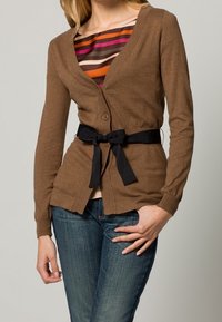 Brauner Cardigan mit V-Ausschnitt, Knopfverschluss und einem schwarzen Stoffgürtel. Die Ärmel sind lang und es gibt zwei vordere Taschen.