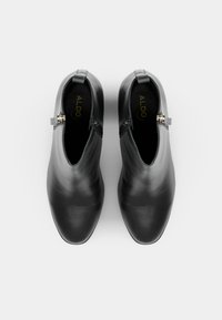 Schwarze Leder-Stiefeletten mit einem eleganten Design, spitzem Zehenbereich und seitlichen Reißverschlüssen. Verfügt über einen subtilen Glanz und goldfarbene Hardware-Details.