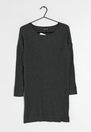 Ciemnoszara sukienka sweterkowa z długim rękawem o fakturze prążkowanej, wisząca na czarnym metalowym wieszaku na białym tle.