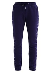 Navy sweatpants with a drawstring waist, featuring metallic studs along the sides and elastic cuffs at the ankles. Soft fabric texture.