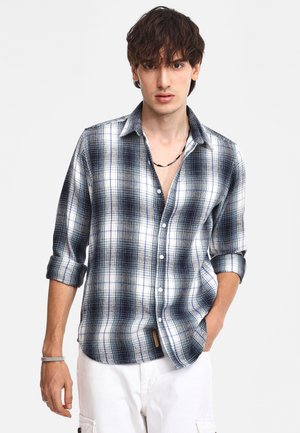 Mannen langelijf geruite shirt in marineblauw en wit, met een button-down kraag, opgerolde mouwen en een gladde, geweven textuur.