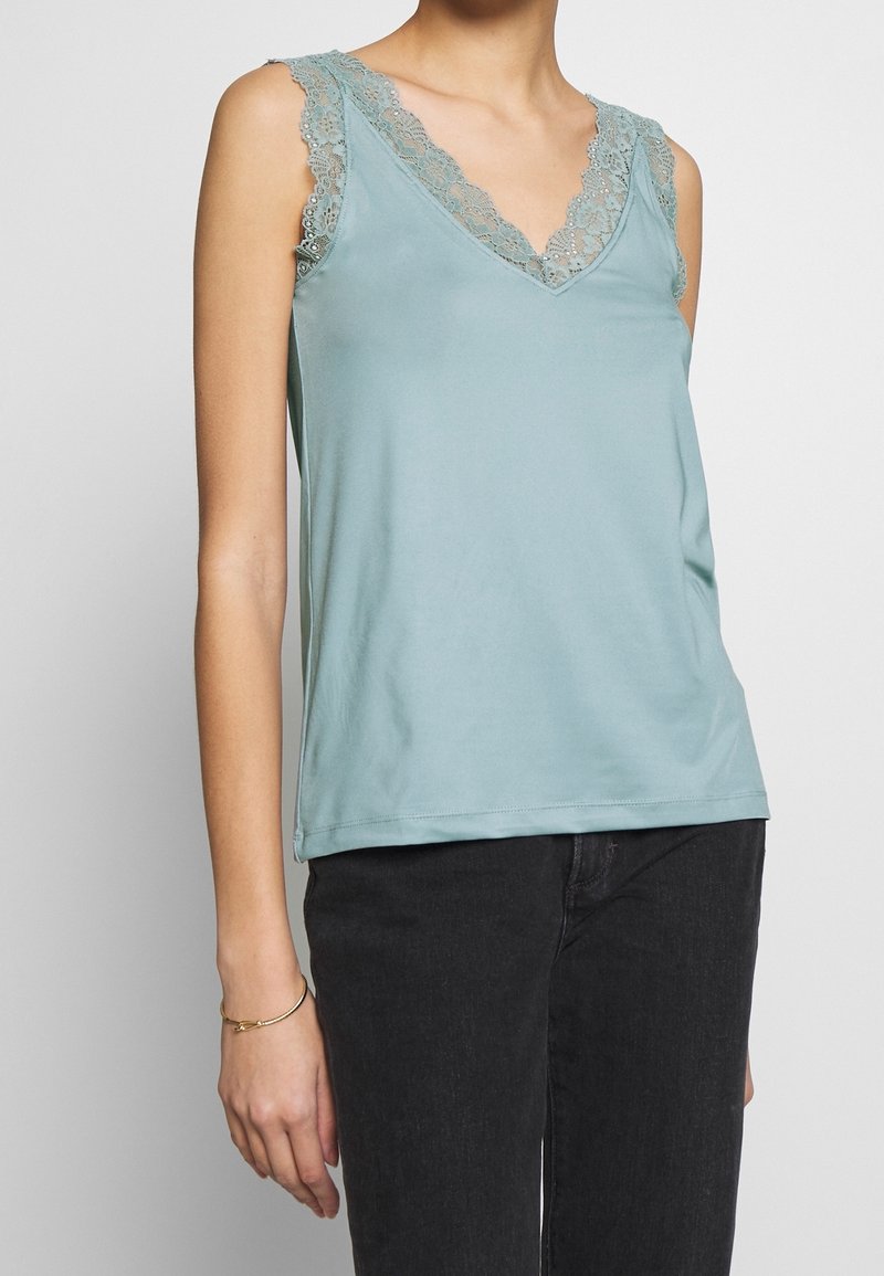 Light blue sleeveless top with a v-neck, features delicate lace trim along the neckline and armholes, made of soft, smooth fabric.