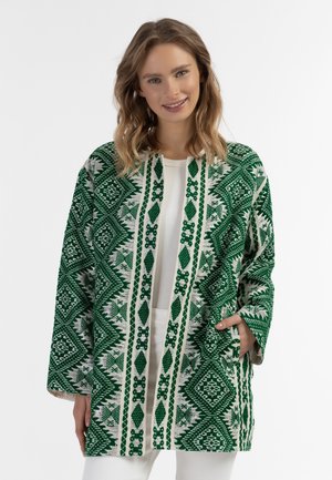 Groene en witte kimono met een geometrisch patroon, brede mouwen en zakken; gemaakt van zacht materiaal en met een ontspannen pasvorm.