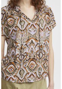 Blouse à manches courtes avec un motif paisley multicolore dans des tons terreux, dotée d'un col en V et d'une texture subtile. Tissu léger.