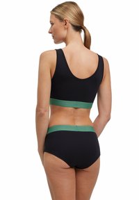 Zwarte sportbeha en set van hooggewaisted slip met een groene elastische band. Glad textuur en eenvoudig ontwerp, dat een klassieke kleurcombinatie benadrukt.