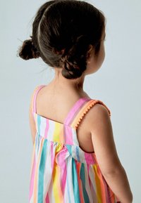 Raidallinen hihaton mekko, jossa on vaaleanpunaisia, keltaisia, sinisiä ja valkoisia värejä, rypytettyjä yksityiskohtia sekä koristellut pompomin reunatolkaimissa.