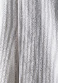 Gestructureerde stof in een lichtgrijze tint, met een verticaal streepmotief. Zacht, grof materiaal met een subtiele glans en een gestructureerd ontwerp.