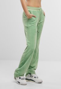 Grønne velour joggebukser med elastisk liv, snøring og to sidelommer, med en glatt tekstur og avslappet passform.