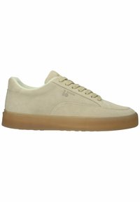 Beige suède sneaker met veters aan de voorkant, gumrubberen zool en een subtiel logo aan de zijkant, gezien vanaf de buitenkant tegen een witte achtergrond.