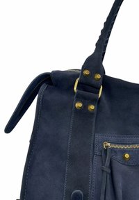 Sac à main en suède bleu marine avec des clous en métal doré, une poche zippée et une anse tressée.