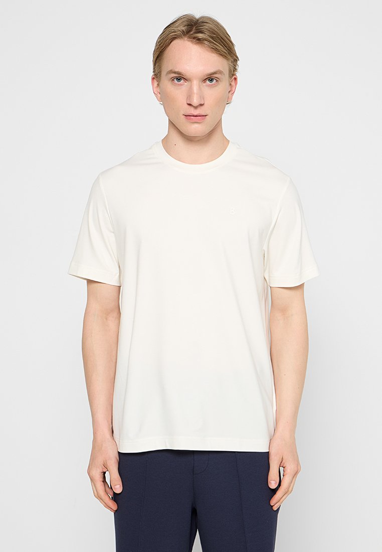 Kurzärmliges T-Shirt mit Rundhalsausschnitt in Cremeweiß. Hergestellt aus glattem Stoff mit einem subtilen Logo-Detail auf der Brust. Klassische, entspannte Passform.