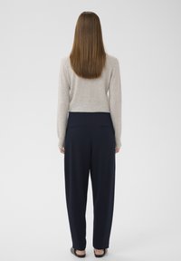 Cremefarvet uldtrøje med lange ærmer, kombineret med marineblå afslappede bukser med baglommer og glat tekstil.
