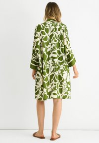 Green and white knee-length dress with a floral pattern, three-quarter sleeves, and a loose fit, made from lightweight fabric.