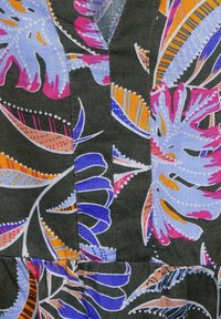 Tekstylia w kwiatowy wzór z żywymi niebieskimi, różowymi, pomarańczowymi i białymi motywami na ciemnym tle; posiada dekolt w kształcie litery V oraz kontrastowe szwy.