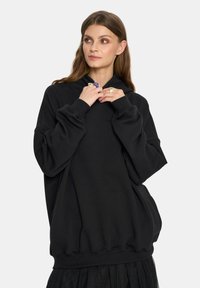 Czarna, oversize bluza z kapturem wykonana z mieszanki bawełny, z długimi rękawami, ściągaczami i kapturem regulowanym sznurkiem. Gładka faktura, minimalistyczny design.
